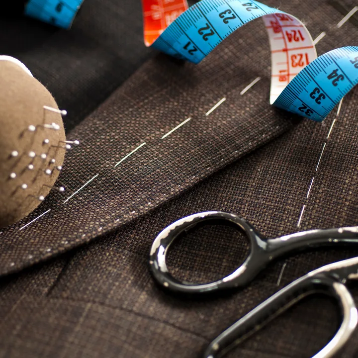 Pièce de tissu épais examinée à l’atelier, avec épingles et ciseaux